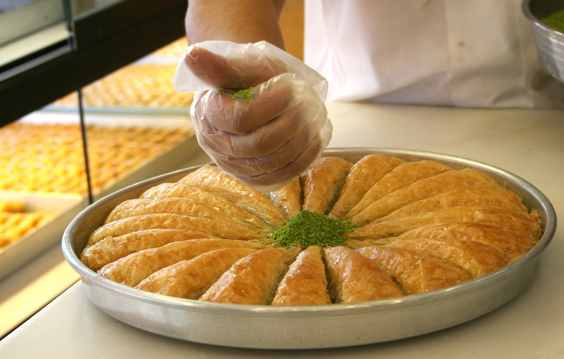 Baklava platter fresh out of the oven being dressed by a chef.