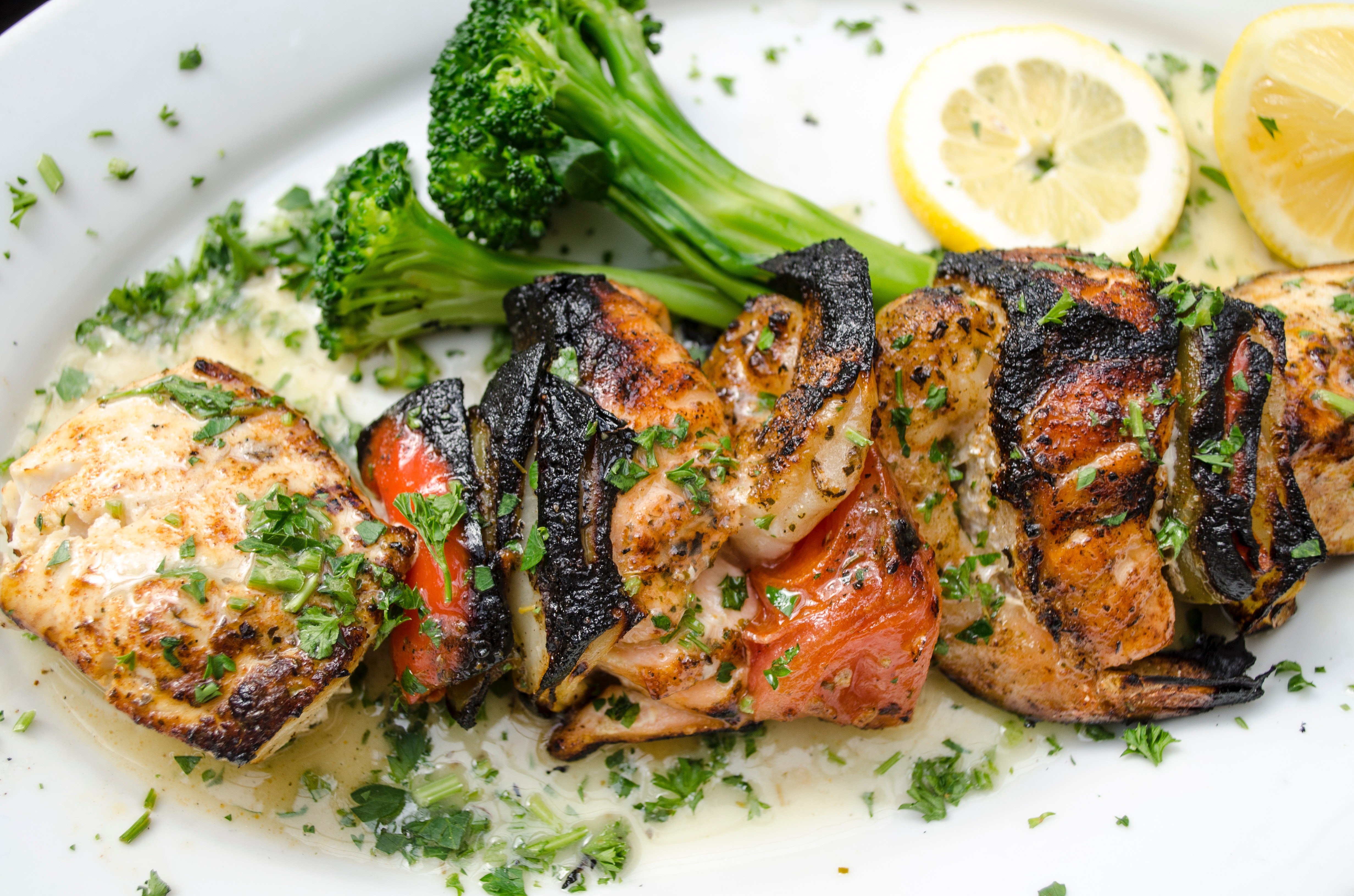Chicken served on a white plate topped with greens.