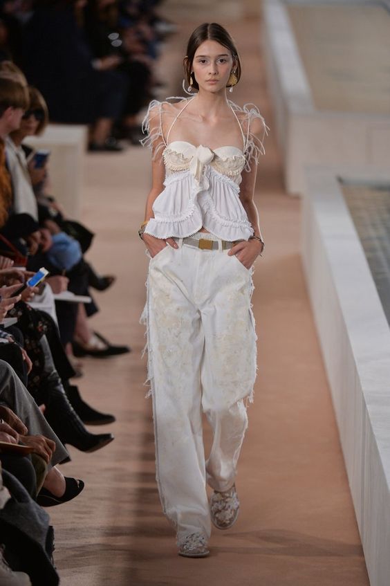 All white runway outfit from 2001. Girl walks down the runway wearing baggy white jeans and a white top.